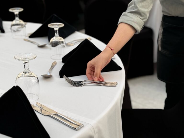 a hand holding a fork and knife on a table